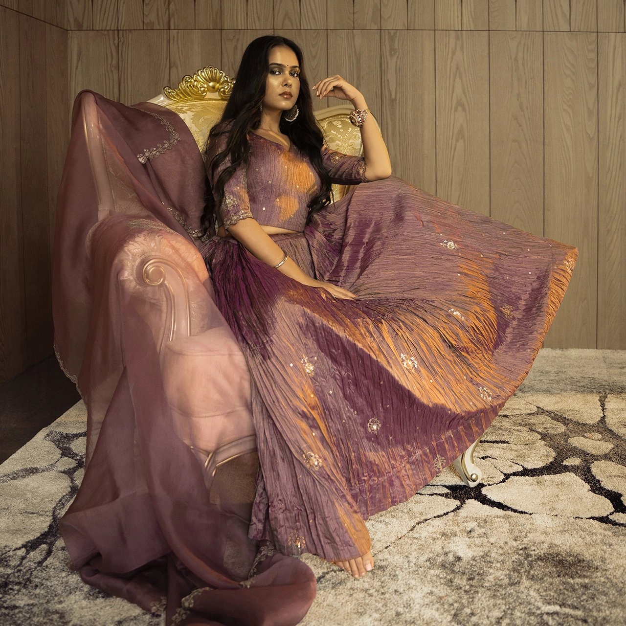 Photography Portfolio Luxury purple and gold designer pleated lehenga fashion photography with model on vintage furniture in elegant interior - Content Crest Media high-end fashion photography portfolio Ahmedabad Gujarat